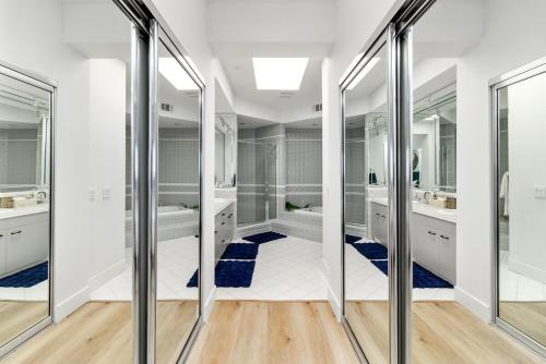 a bathroom with two sinks and two mirrors at Pacific Passion Beach House in Carlsbad