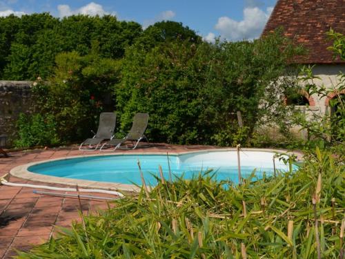 - une piscine avec deux chaises dans la cour dans l'établissement Gîte de charme avec piscine au cœur de la Brenne, idéal pour nature et détente - FR-1-591-288, à Chalais