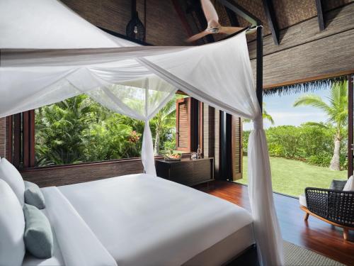 a bedroom with a bed and a large window at Six Senses Fiji in Malolo