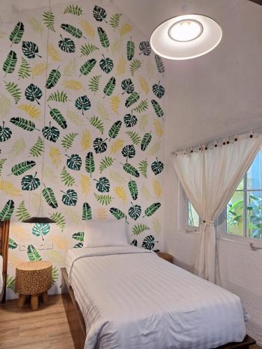 a bedroom with a bed and a wall with leaves at InN House Homestay in Dadapan