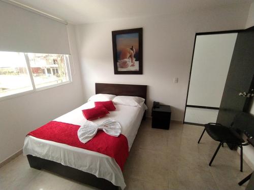 a bedroom with a bed with a red and white blanket at Hotel California Air in Carepa