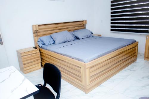 a wooden bed with blue pillows in a bedroom at UNIA Homes in Benin City