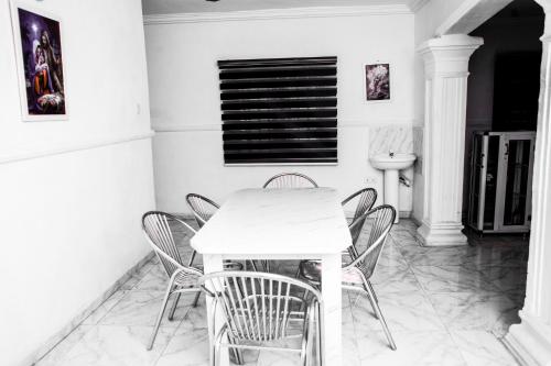 a white dining room with a white table and chairs at UNIA Homes in Benin City