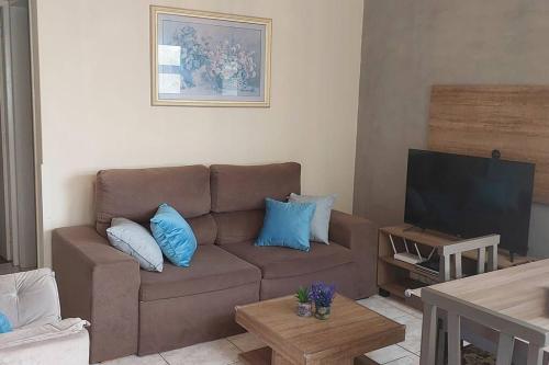 a living room with a brown couch with blue pillows at Apartamento amplo na Beira Mar de Tramandaí-RS in Tramandaí