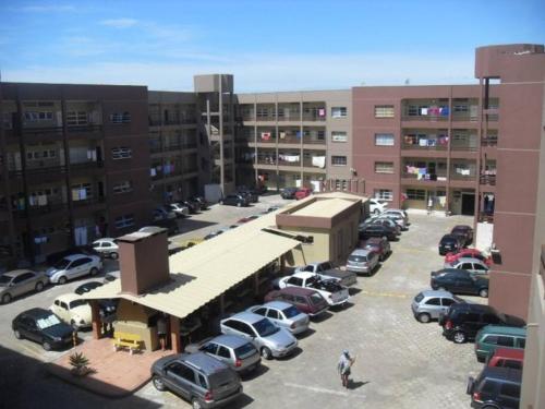 a parking lot with cars parked in front of buildings at Apartamento amplo na Beira Mar de Tramandaí-RS in Tramandaí