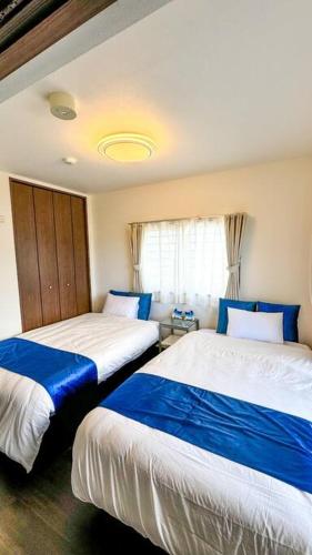 two beds in a room with blue and white at ocean terrace SESOKO 301 in Ufugumui