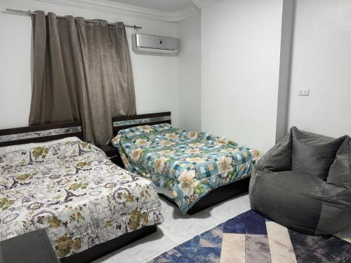 a room with two beds and a couch and a chair at شقة على كورنيش النيل المعادي Maadi Nile view Cairo in Al Ma‘şarah