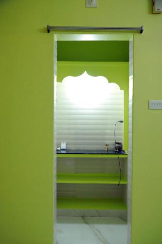 a room with a green wall with a shelf with a window at srisaisrinivasahomestay in Tirupati