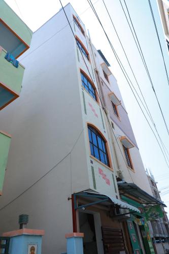 a tall white building with the front of it at srisaisrinivasahomestay in Tirupati