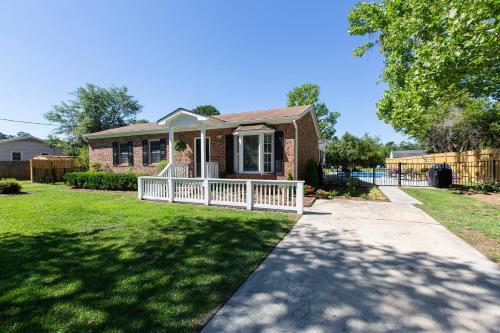 a brick house with a white fence in a yard at Coastal Home with Inground Pool in Wilmington