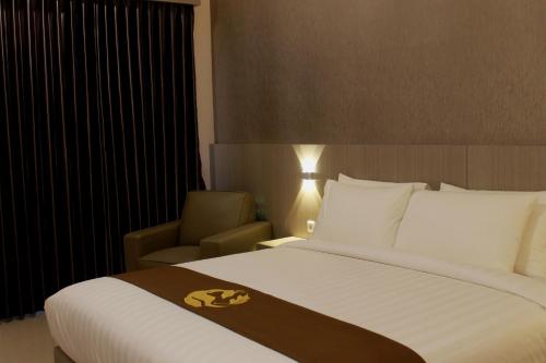 a hotel room with a large bed and a chair at Gets Hotel in Malang