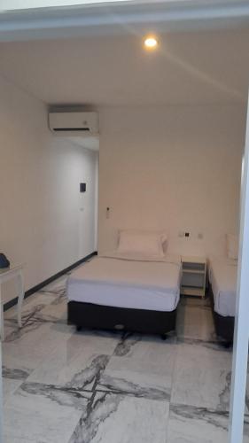 two beds in a room with a marble floor at Beach Hotel Wirton Batukaras in Batukaras