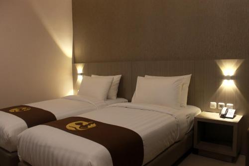 two twin beds in a hotel room with lights at Gets Hotel in Malang