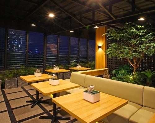 a restaurant with tables and a couch in a room at Mimaru Hotel Jakarta Mangga Besar in Jakarta