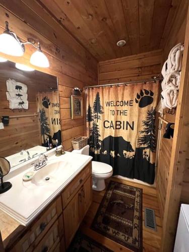 a bathroom with a sink and a toilet and a shower curtain at Ultimate Log Cabin Experience with BREATHTAKING Views in Yonah