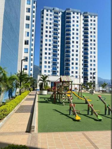 a playground with play equipment in a park with tall buildings at Moderno y central apartamento in Vallecito
