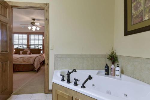 a bathroom with a white sink and a bedroom at Sooner Settle Lodge 4 King Rooms Stonebridge in Reeds Spring