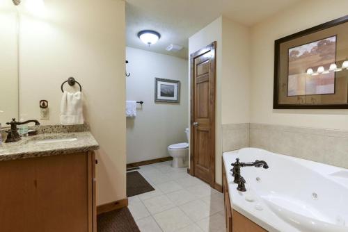 a bathroom with a tub and a sink and a toilet at Sooner Settle Lodge 4 King Rooms Stonebridge in Reeds Spring