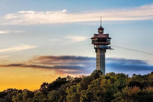 a tower on top of a hill with a sunset at Sooner Settle Lodge 4 King Rooms Stonebridge in Reeds Spring