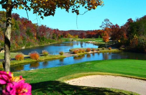 a view of a golf course with a river at Sooner Settle Lodge 4 King Rooms Stonebridge in Reeds Spring