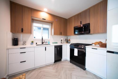 a kitchen with white cabinets and black appliances at Modern Ocean Beach Apartment in San Diego