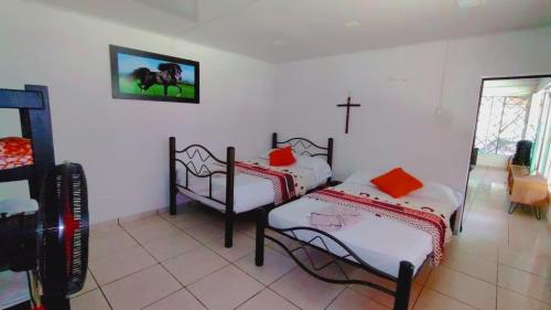 a room with two beds and a cross on the wall at Casa Campestre San Joaquin in Restrepo