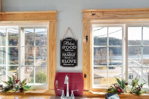a kitchen with two windows and a sign on the wall at Historic Rockaway Beach Cottage in Rockaway Beach
