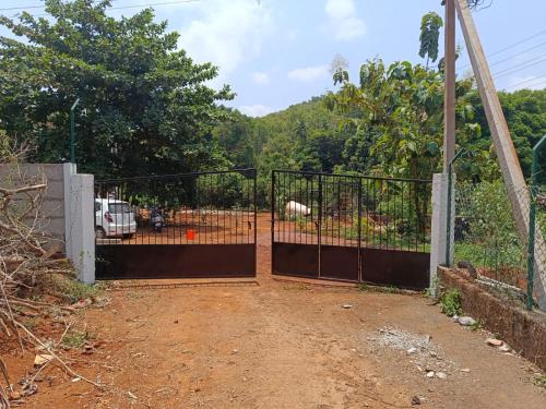 an open gate with a fence in a field at Ecoark Farmstay in Cuncolim