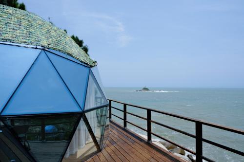 a glass house on a deck overlooking the water at 东山一个庐野奢帐篷营地 in Yanya