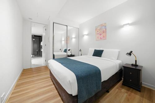 a bedroom with a large bed with a blue blanket at Flinders Street Apartments in Melbourne