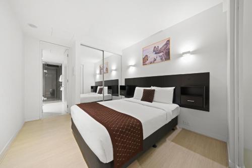 a bedroom with a large bed in a white room at Flinders Street Apartments in Melbourne