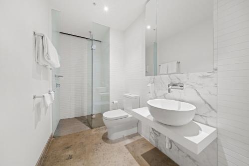 a white bathroom with a sink and a toilet at Flinders Street Apartments in Melbourne