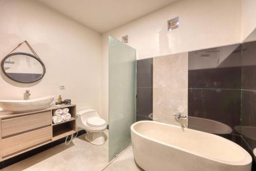 a bathroom with a tub and a sink and a toilet at Kelingking Parama Resort in Nusa Penida