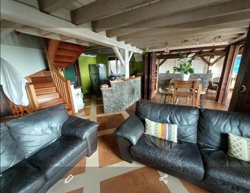 a living room with a leather couch and a dining room at Villa Créolia in Saint-Leu
