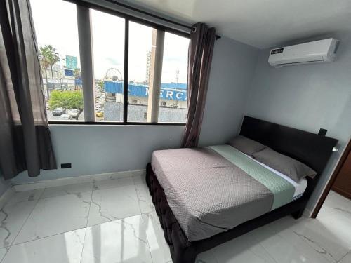 a small bedroom with a bed and a large window at Scotland Hotel in Guayaquil