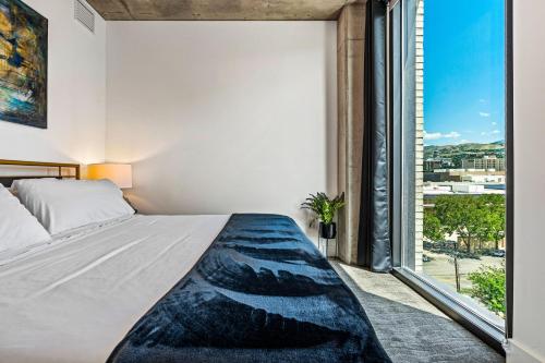 a bedroom with a bed and a large window at Exceptional 1BD BA-PoolHotTubGymParking- Downtown! in Salt Lake City