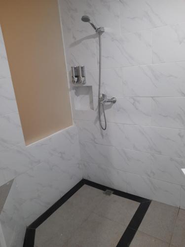 a bathroom with a shower with white tiles at Beach Hotel Wirton Batukaras in Batukaras