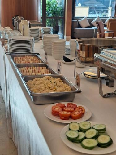 a buffet of food with cucumbers and tomatoes on plates at Thomson Residence Hotel in Bangkok