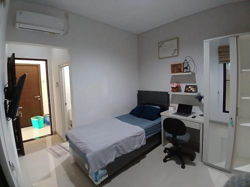 a bedroom with a bed and a desk with a laptop at Oren Stayz ICE BSD in Pagedangan