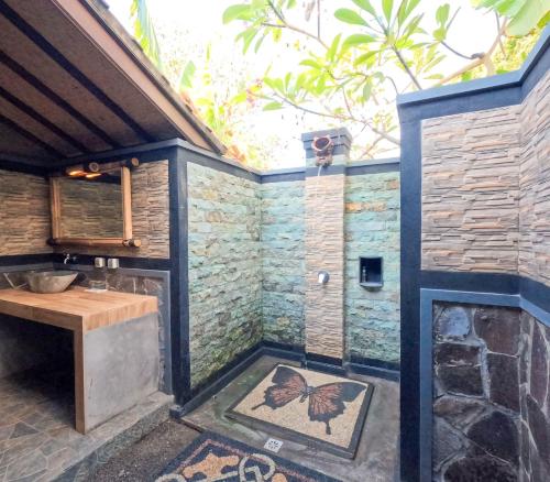 a bathroom with a butterfly mosaic on the wall at Suka Sari Cottages in Pemuteran