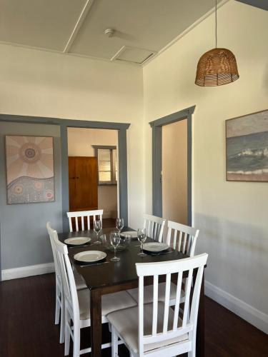 a dining room with a table and white chairs at Full house in the centre of town in Bellingen