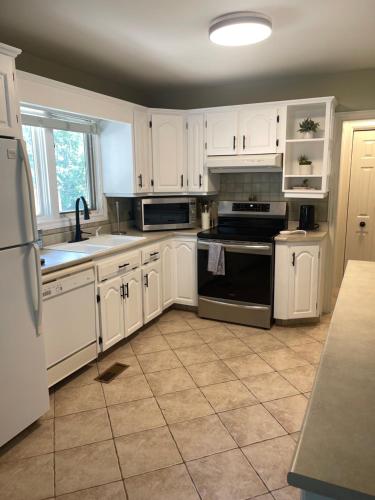 a kitchen with white cabinets and appliances and a tile floor at University Manor in Moncton