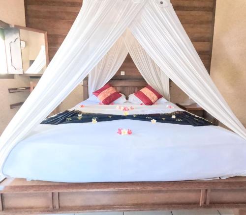 a bed with white sheets and pillows in a room at Suka Sari Cottages in Pemuteran