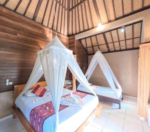 a bedroom with two beds with mosquito nets at Suka Sari Cottages in Pemuteran