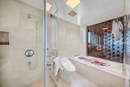 a bathroom with a tub and a toilet and a shower at Paris Deli Danang Beach Hotel in Da Nang