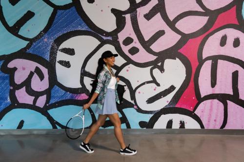 a woman walking past a wall with a tennis racket at Aloft Orlando Lake Nona in Orlando