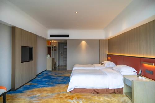 a hotel room with two beds and a television at 长沙荔高尊享酒店 in Changsha