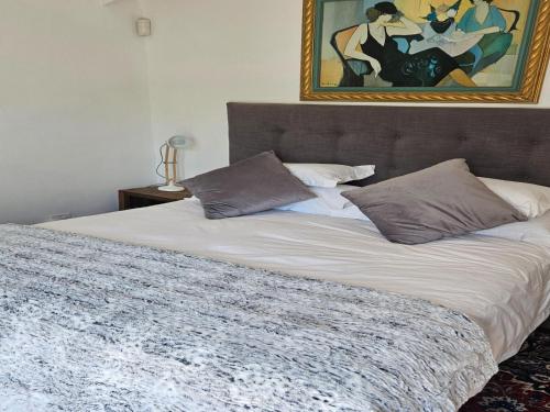 ein Bett in einem Schlafzimmer mit einem Gemälde an der Wand in der Unterkunft PinotageLuxuryCollection 9A Herte Suite in Stellenbosch