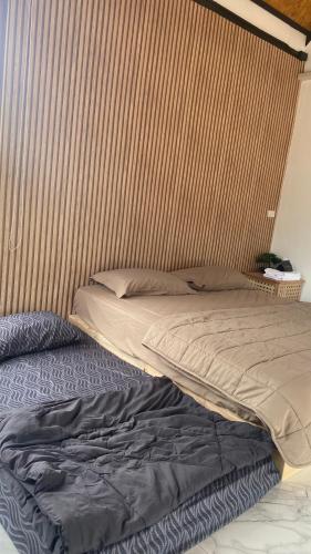 a bed in a bedroom with a wooden wall at 4U Resort & Camp in Ban Kampong Ba-Ru
