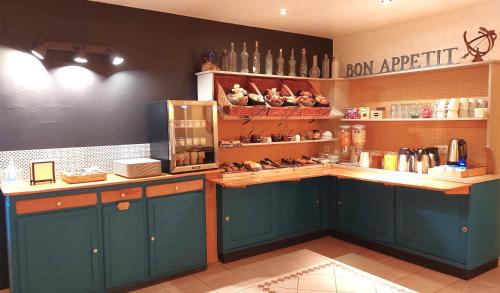 una cucina con un bancone con mobili blu e uno scaffale di Logis Hôtel La Rosière----Situé entre BAYEUX et ARROMANCHES a Tracy-sur-Mer